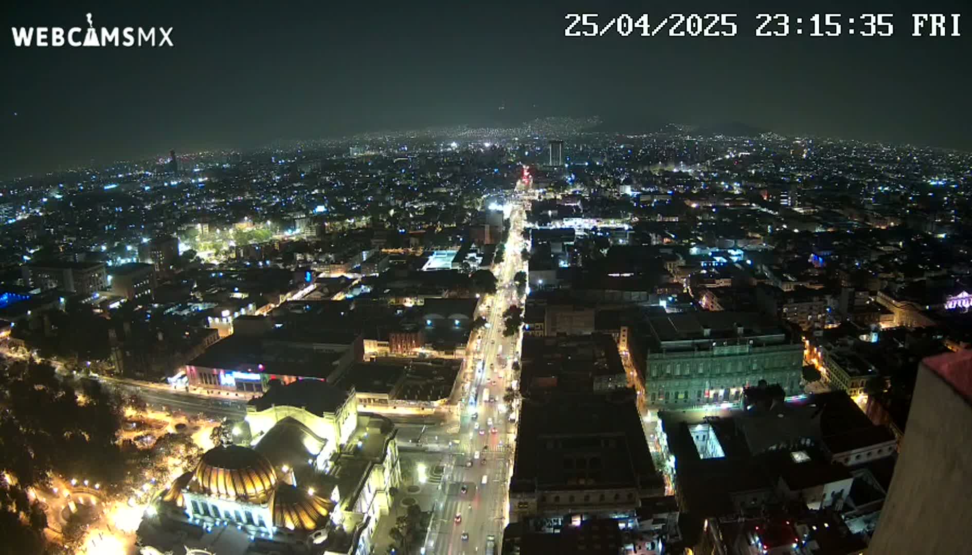 A nighttime, high-angle view of a sprawling city with brightly lit streets and buildings.
