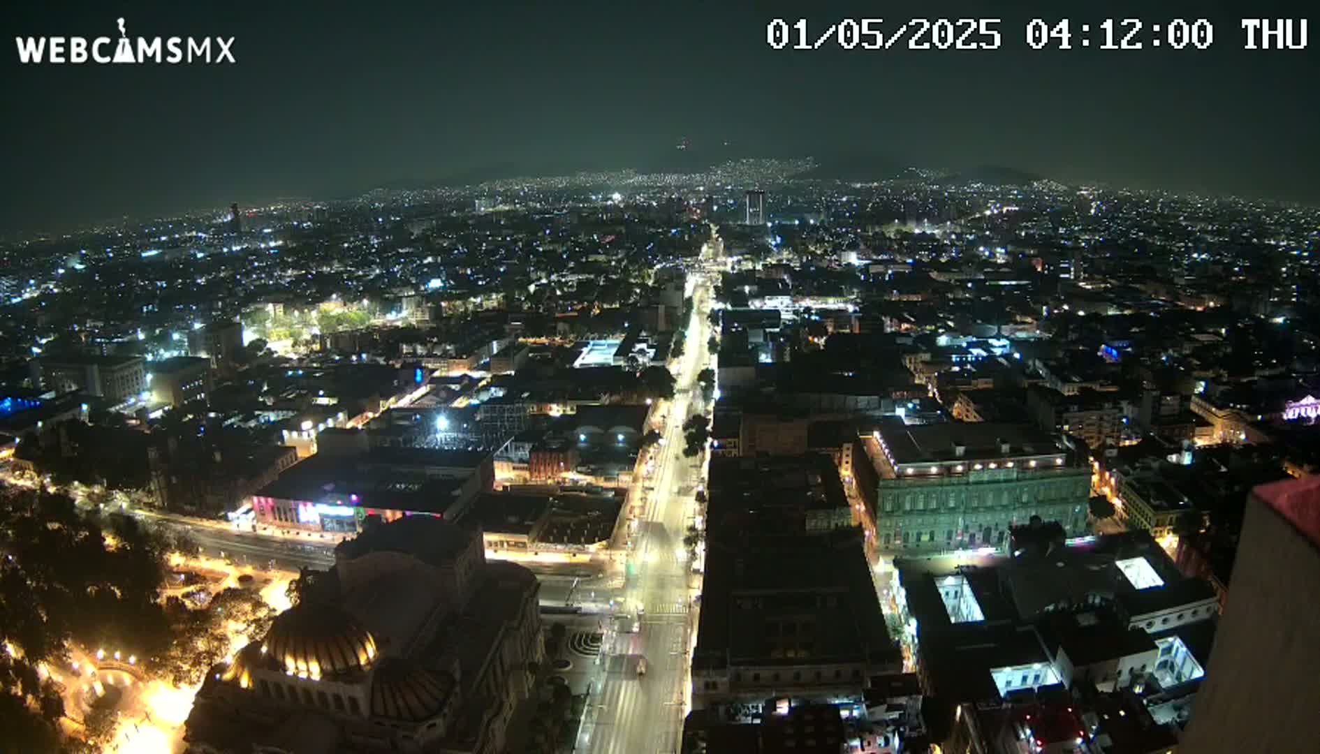 A nighttime aerial view of a city with illuminated streets and buildings under a clear sky.
