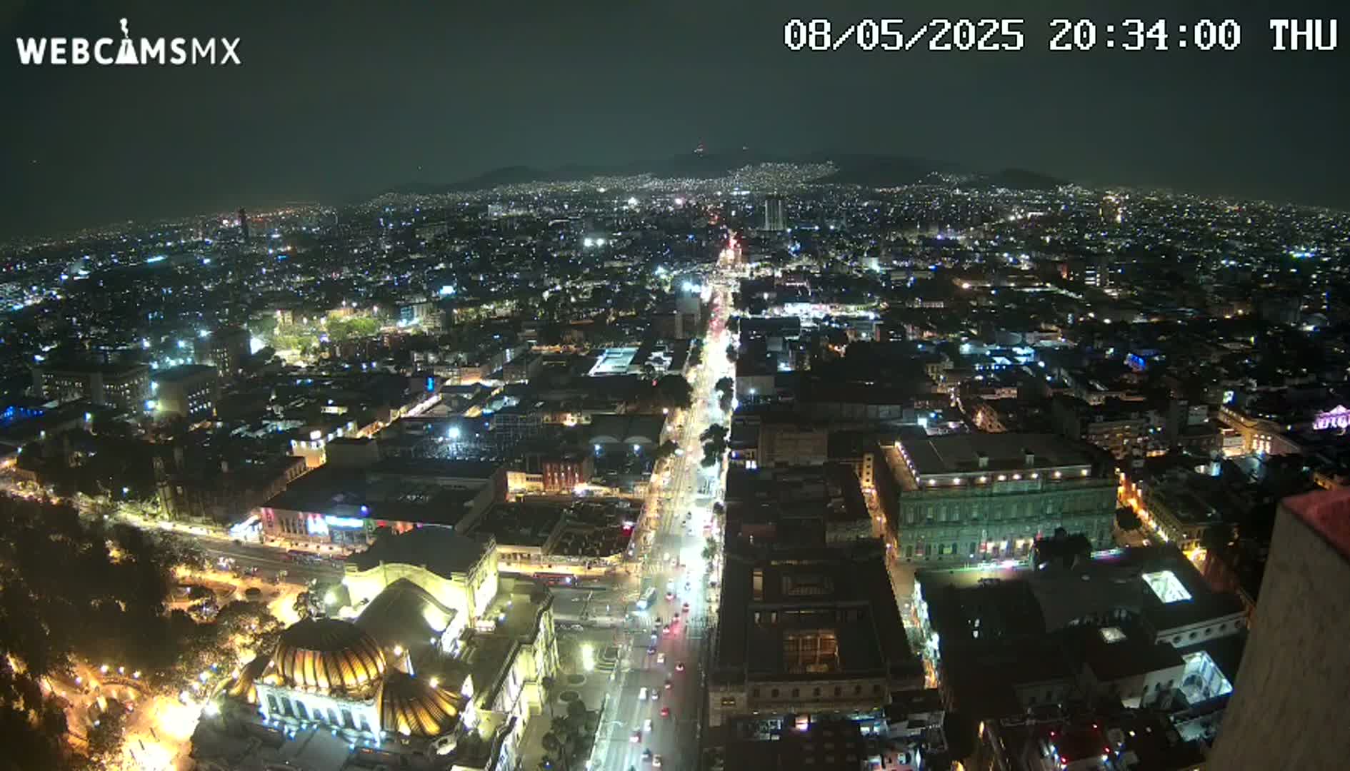 A nighttime aerial view of a brightly lit city with a long, illuminated road running through it.