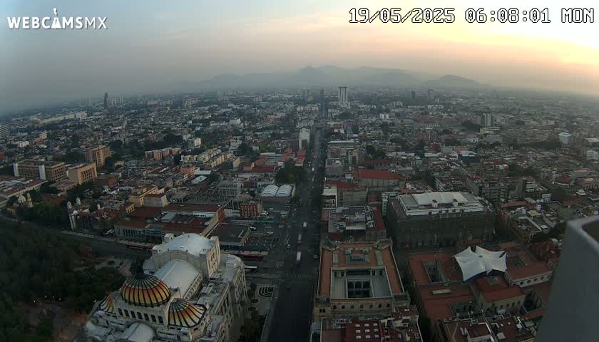 An aerial view of a large city on a hazy day, showing a long street leading to a large domed building.