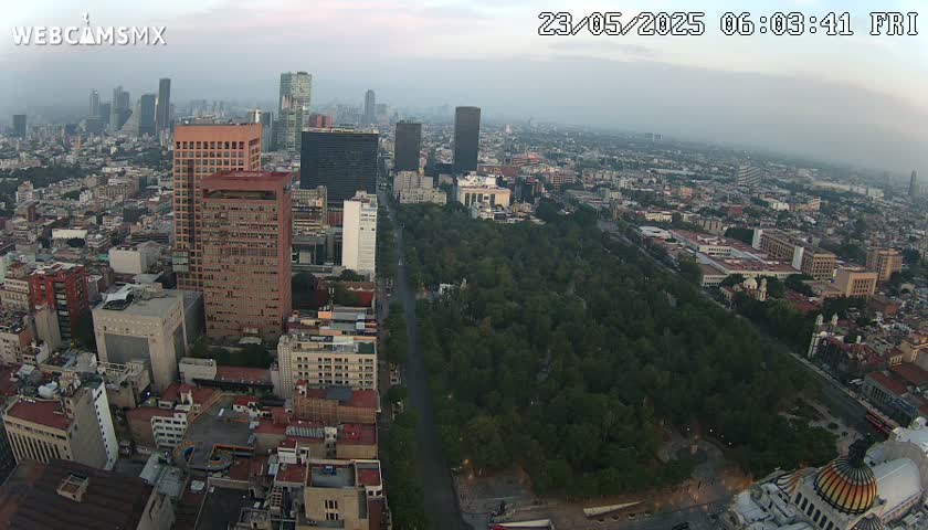 An aerial view of a city with many buildings and a large park in the center, under hazy skies.