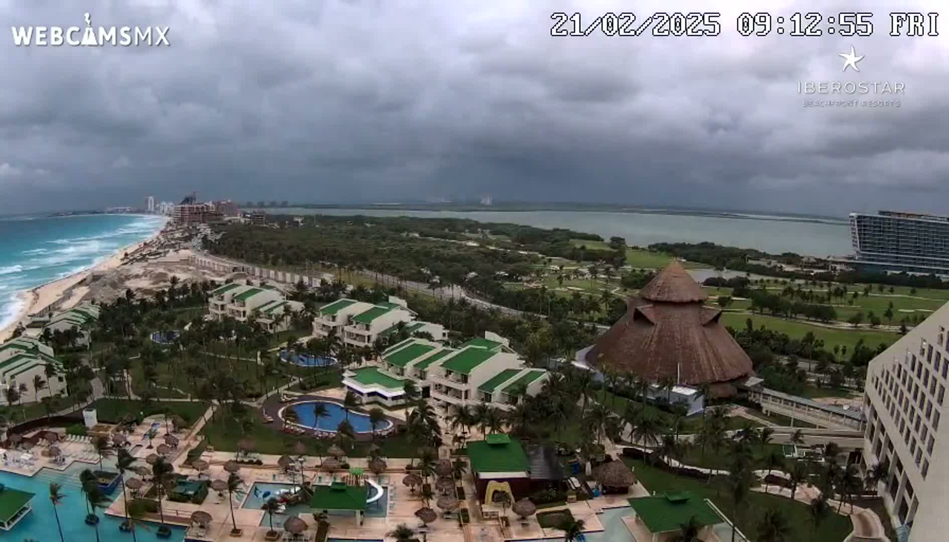 An aerial view of a resort on a beach with overcast skies and waves crashing on the shore.