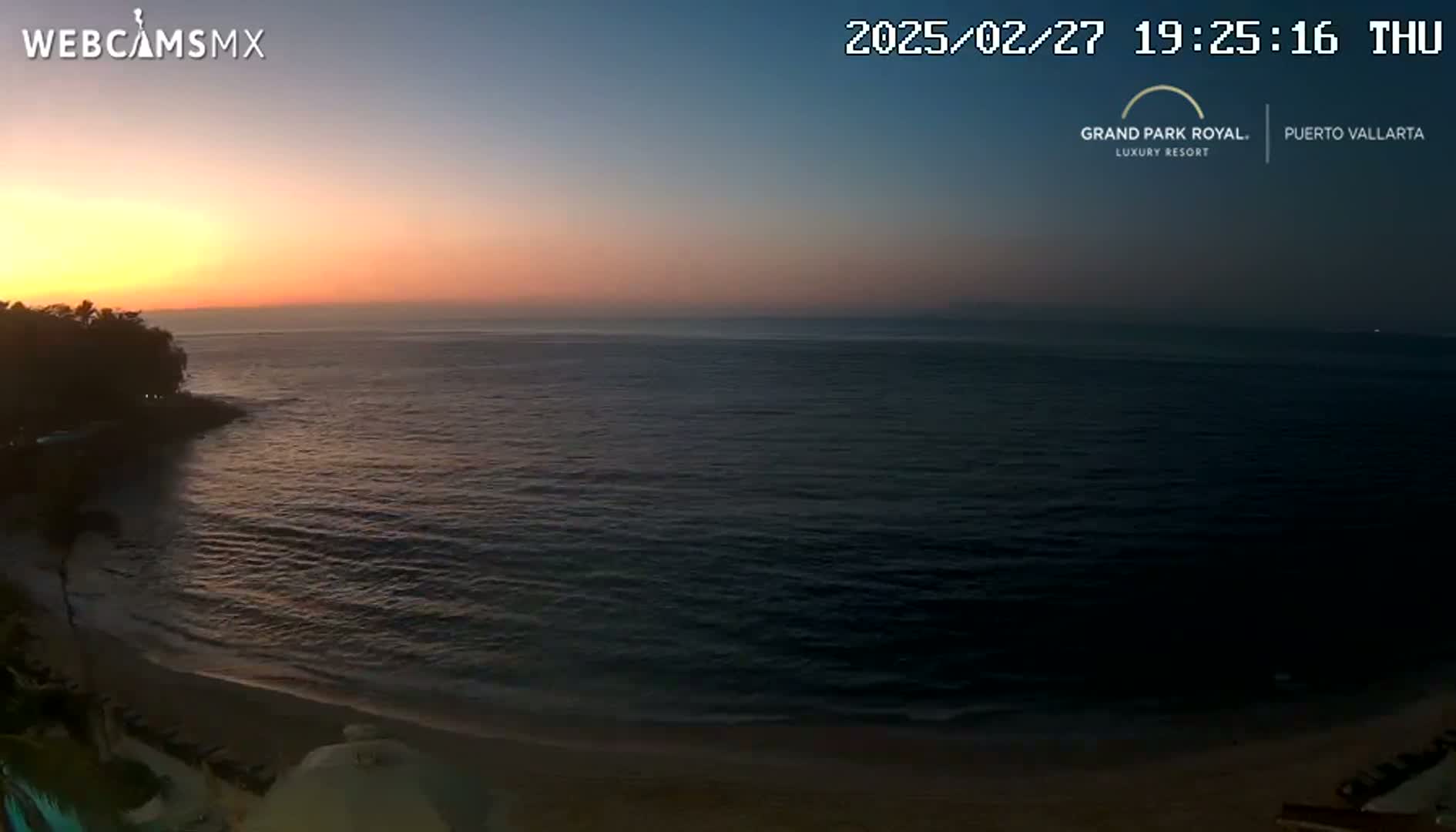 A beach at sunset with calm ocean waters.