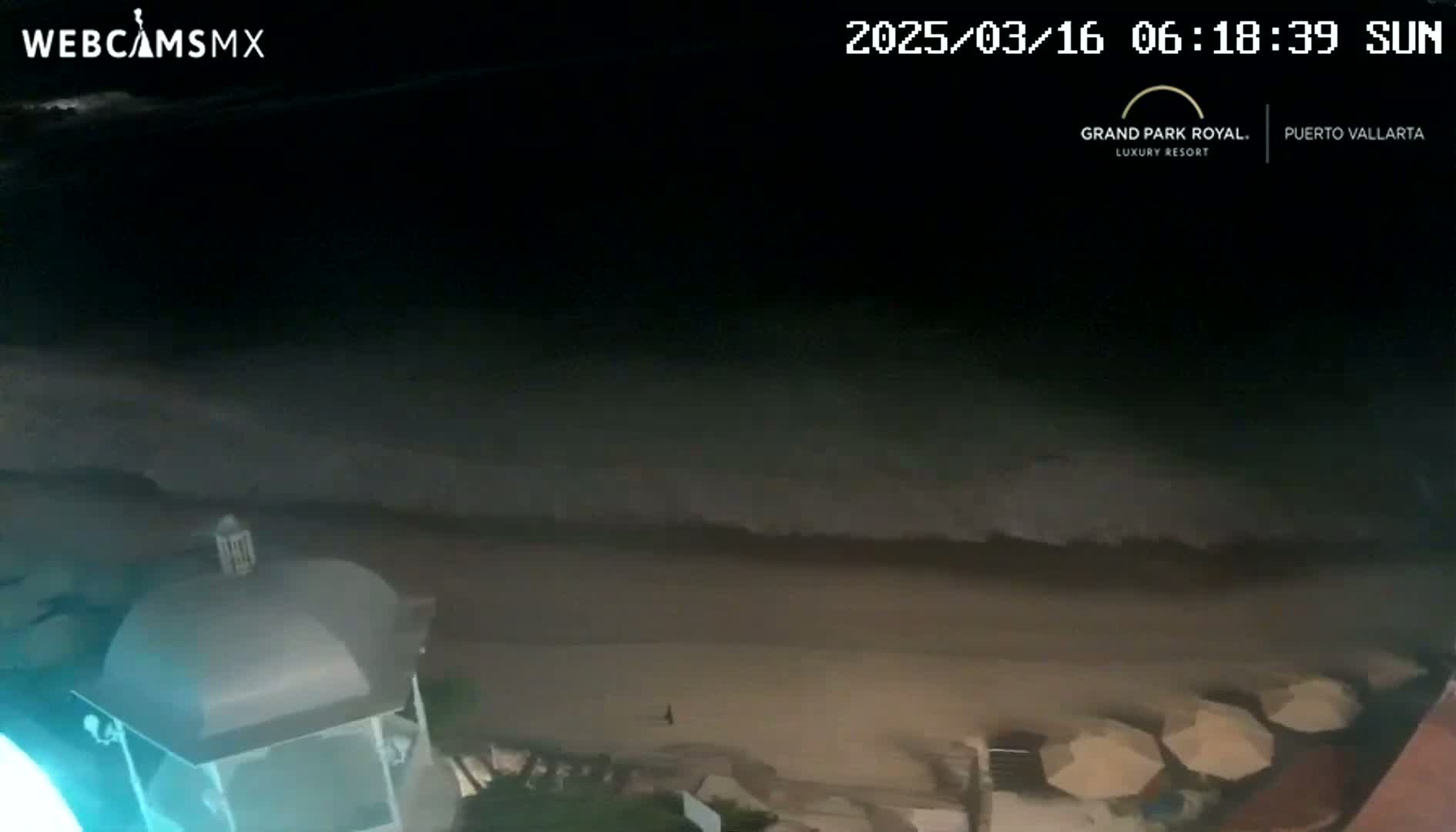 A nighttime beach scene shows dark waves lapping at the shore near a building with a domed roof, and several indistinct objects on the sand.