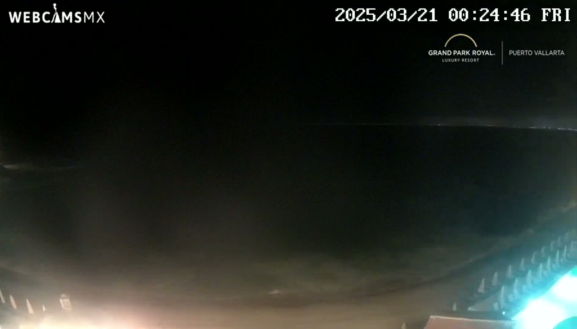 A dark, nighttime beach scene is visible, with calm water and faintly lit beach chairs in the bottom right corner.