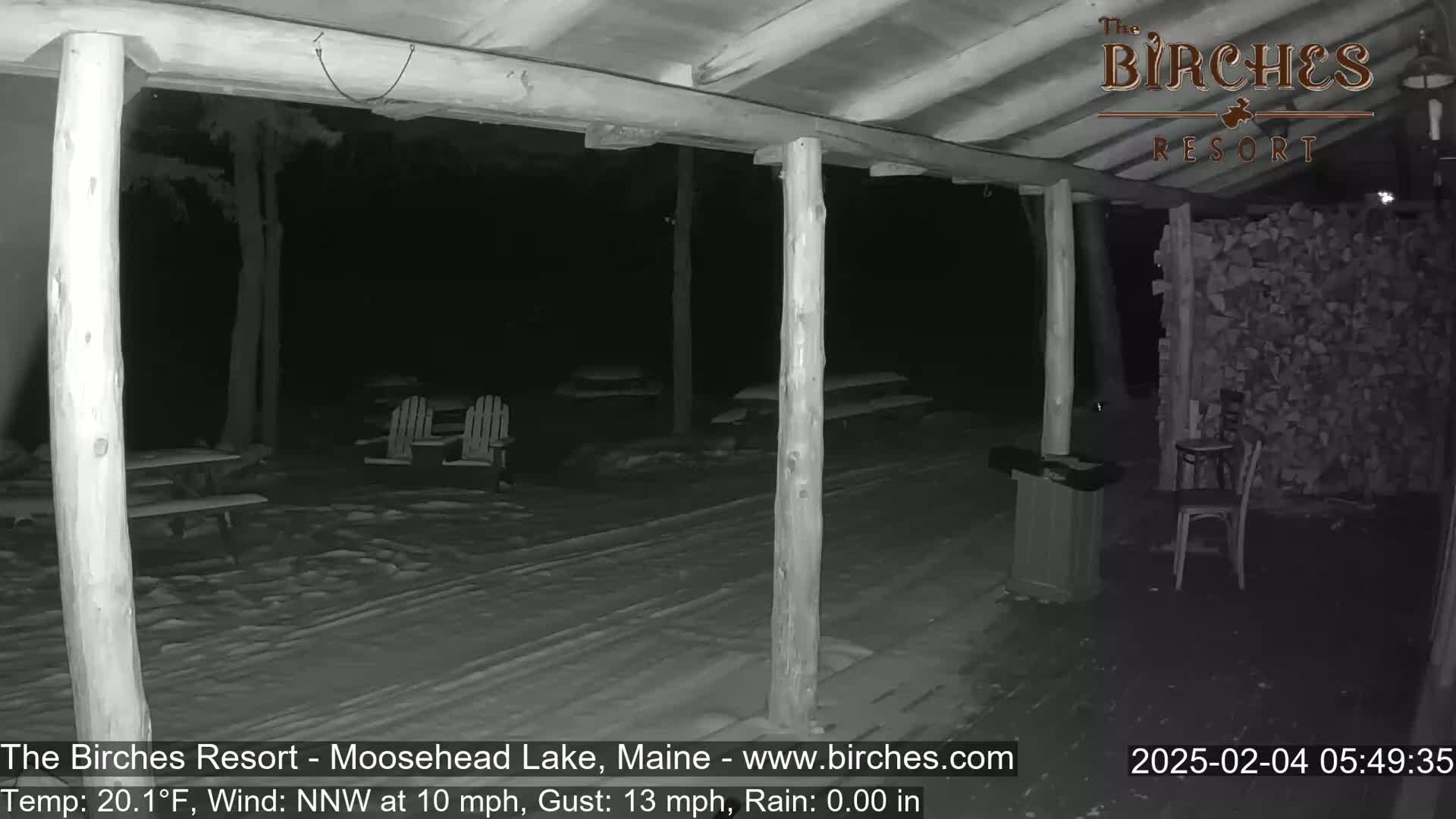 A snow-covered outdoor patio area with wooden posts, picnic tables, and chairs is visible at night under a NNW wind of 10 mph with gusts up to 13 mph and a temperature of 20.1°F.