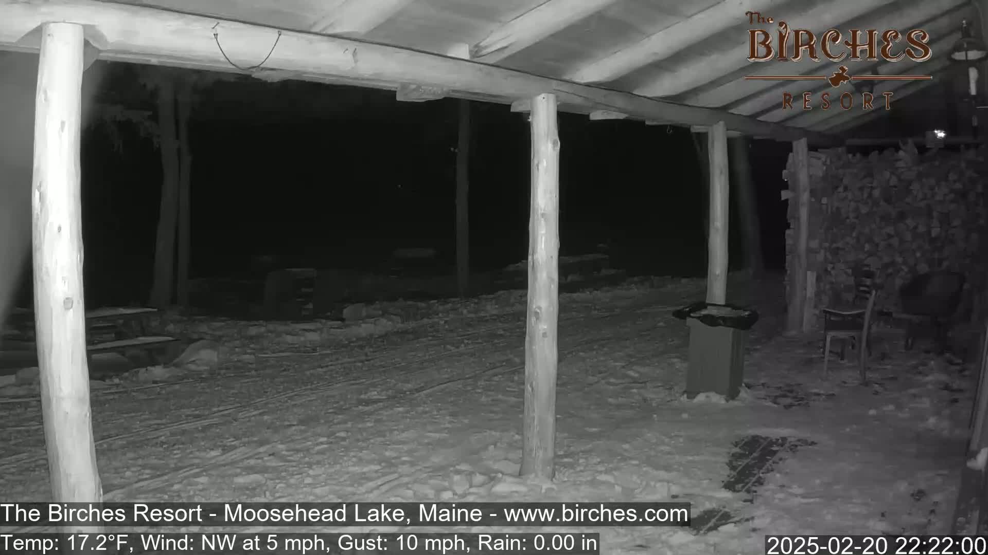 A snow-covered outdoor area at night, under a wooden covered structure, with a northwest wind blowing at 5 mph and gusts of 10 mph.