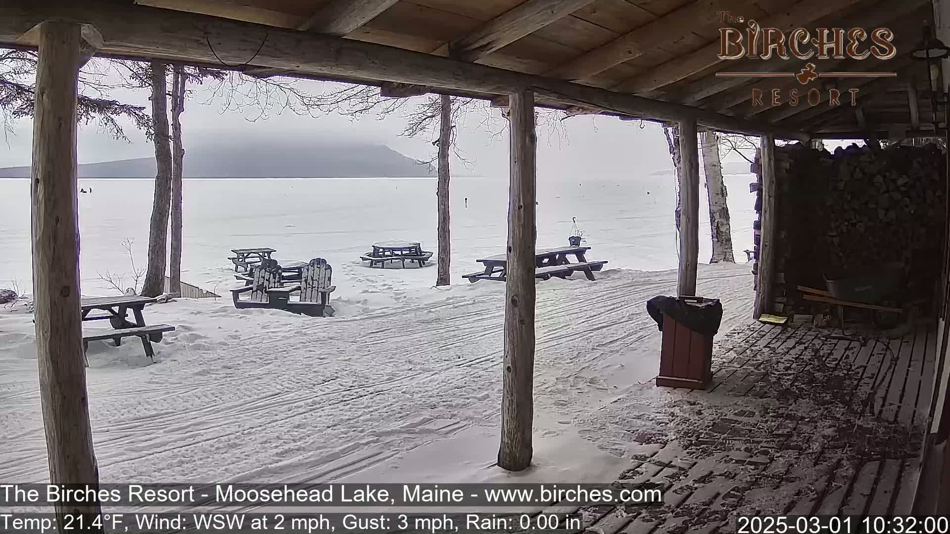 A snow-covered porch overlooks a frozen lake under an overcast sky.