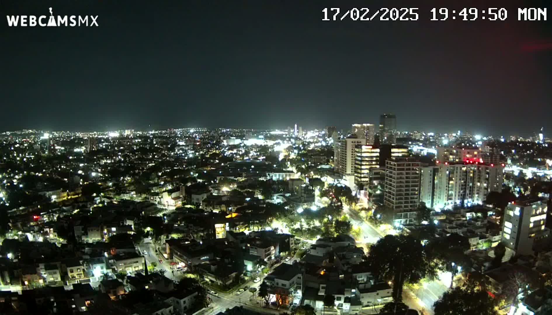 A nighttime aerial view of a city illuminated by streetlights and building lights under a clear, dark sky.