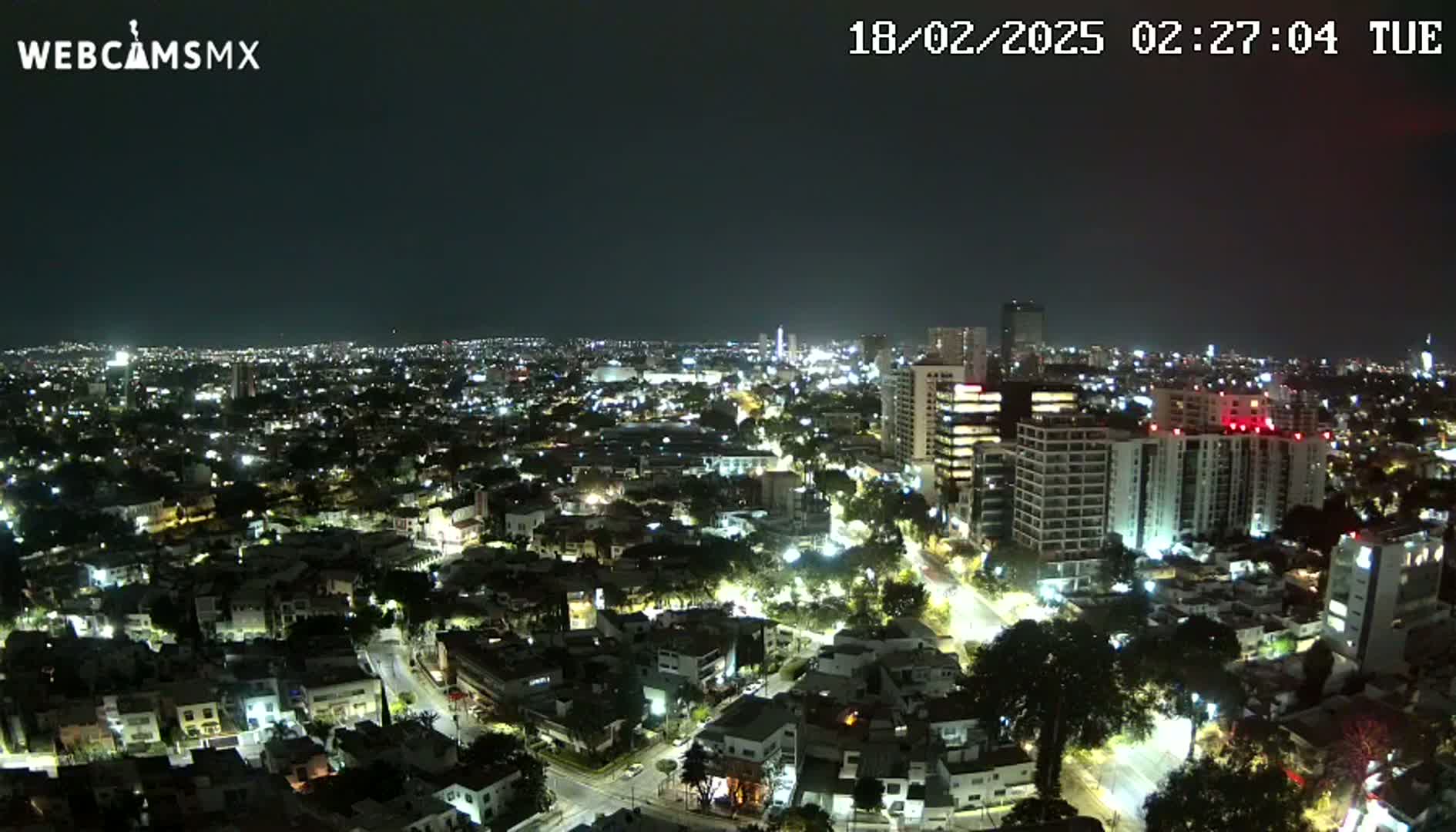 A nighttime aerial view of a city illuminated by streetlights and building lights under a clear, dark sky.