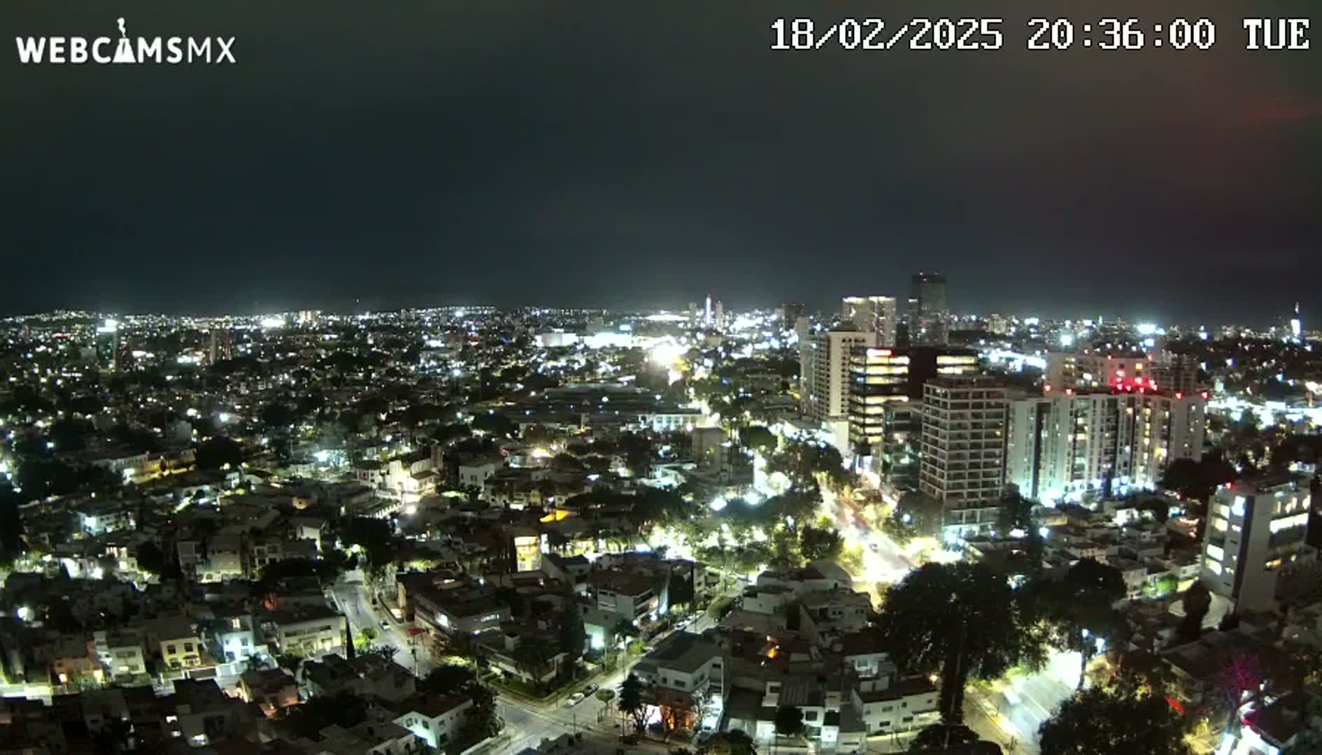 A nighttime aerial view of a city with numerous illuminated buildings and streets.