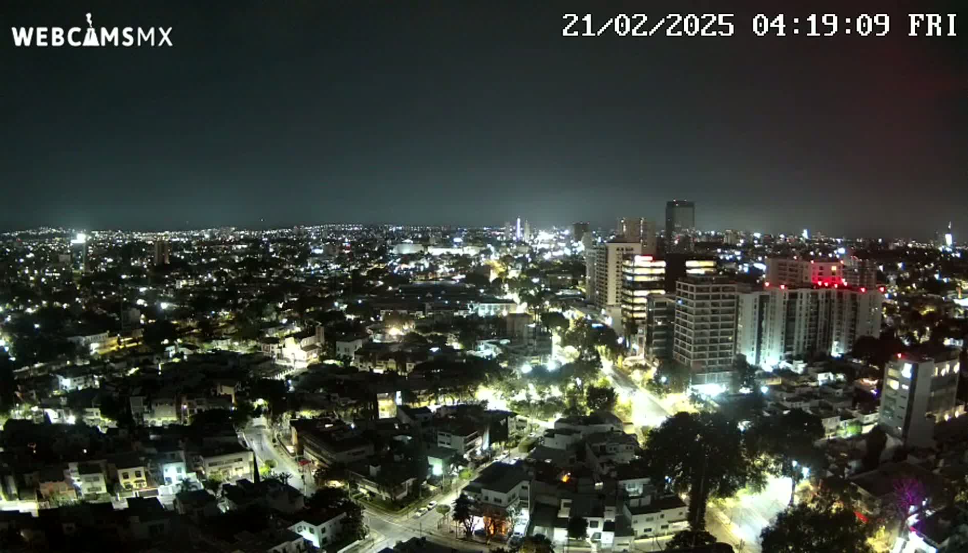 A nighttime aerial view of a city illuminated by streetlights and building lights under a clear, dark sky.