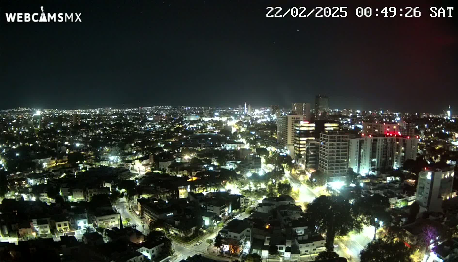 A nighttime, aerial view of a city illuminated by streetlights and building lights under a clear, starry sky.
