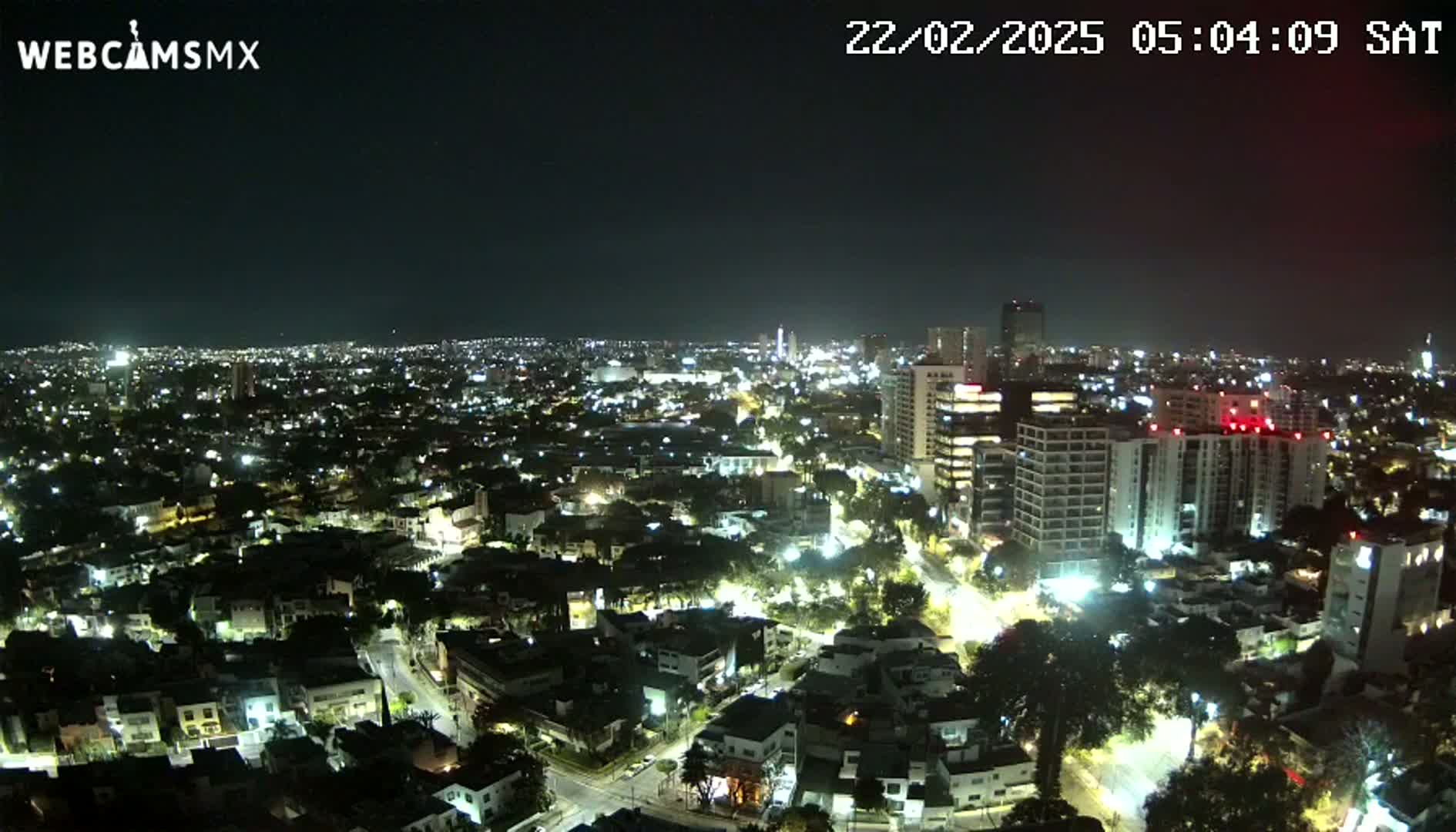 A nighttime aerial view of a city illuminated by streetlights and building lights under a clear, dark sky.