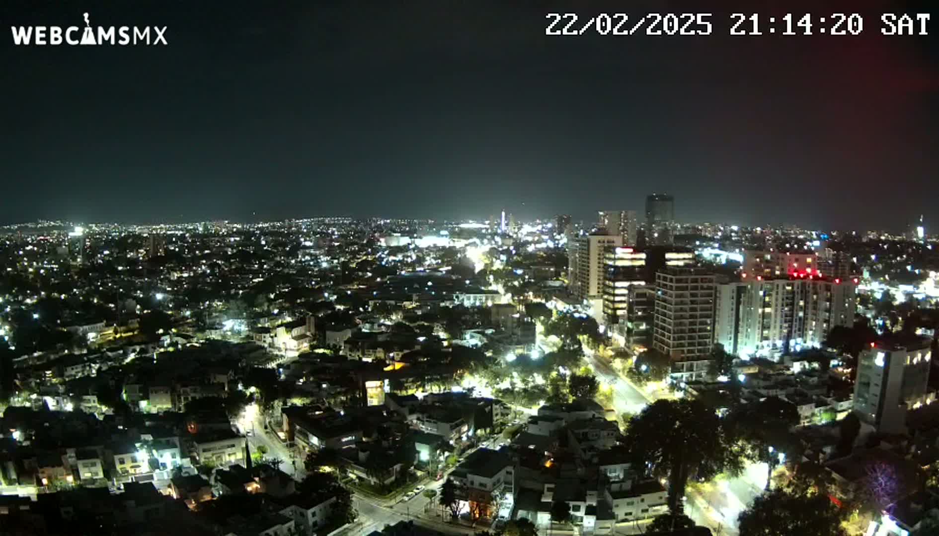 A nighttime aerial view of a city illuminated by streetlights and building lights under a clear sky.