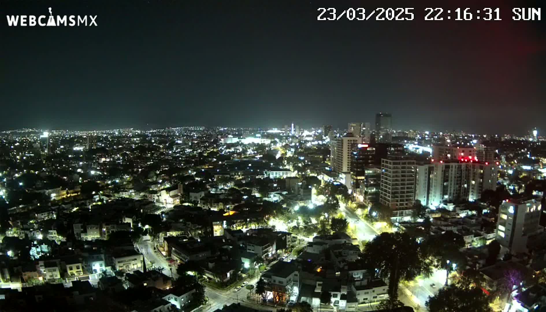 A nighttime aerial view of a sprawling city illuminated by streetlights and building lights under a clear, dark sky.