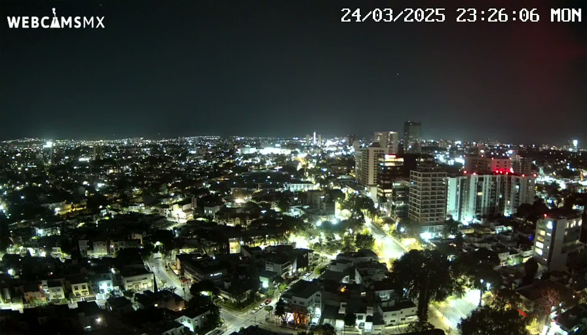 A nighttime aerial view of a city illuminated by streetlights under a clear sky.