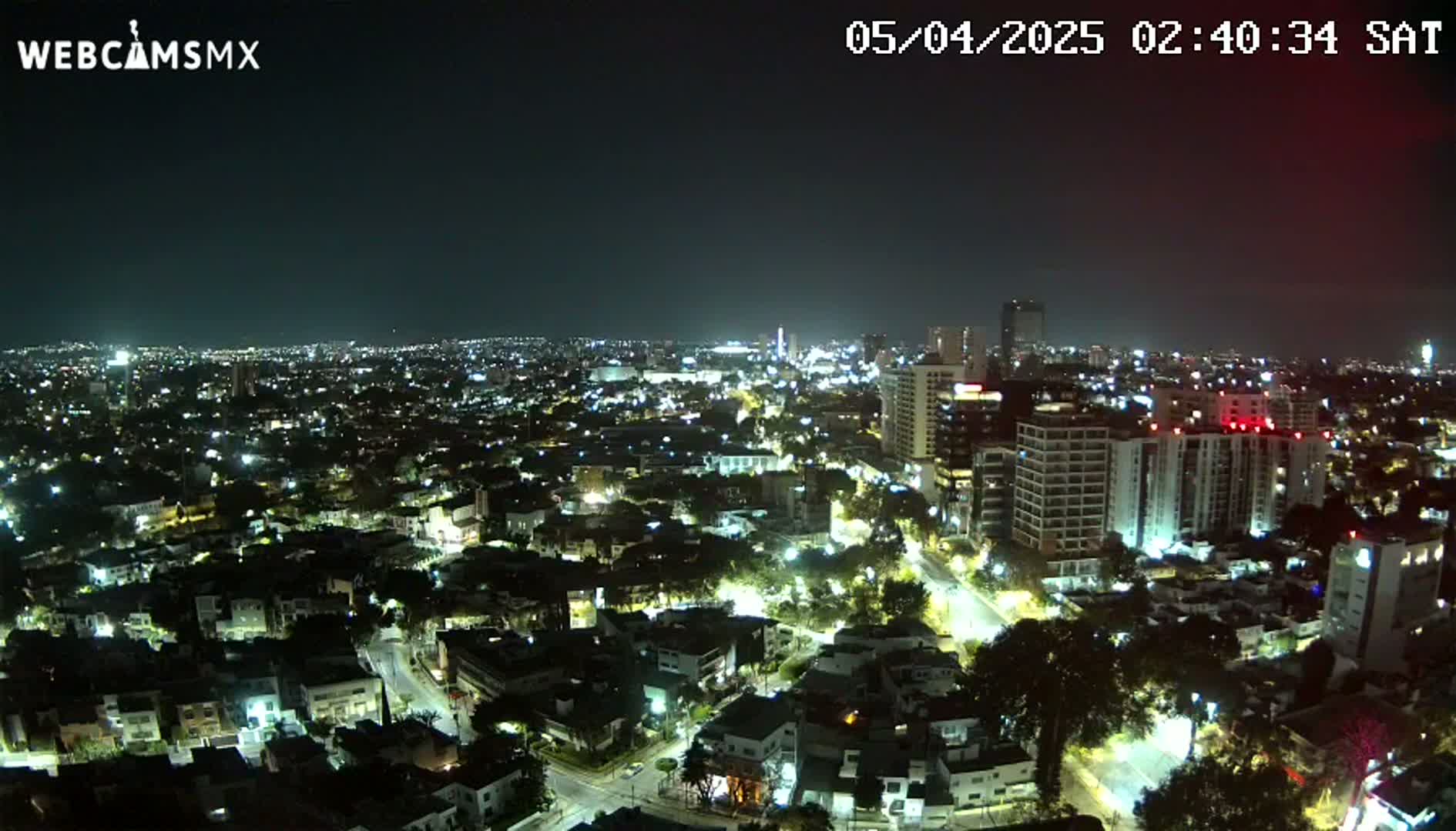 A nighttime, high-angle view of a city illuminated by streetlights and building lights.