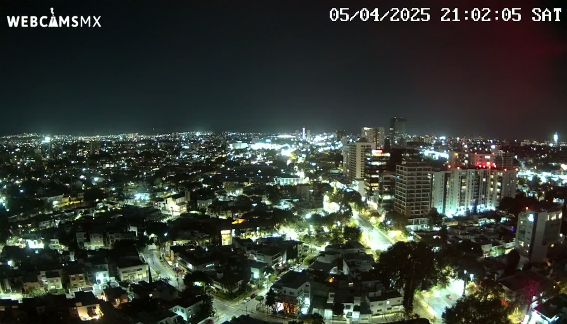A nighttime aerial view of a city illuminated by streetlights and building lights under a clear sky.