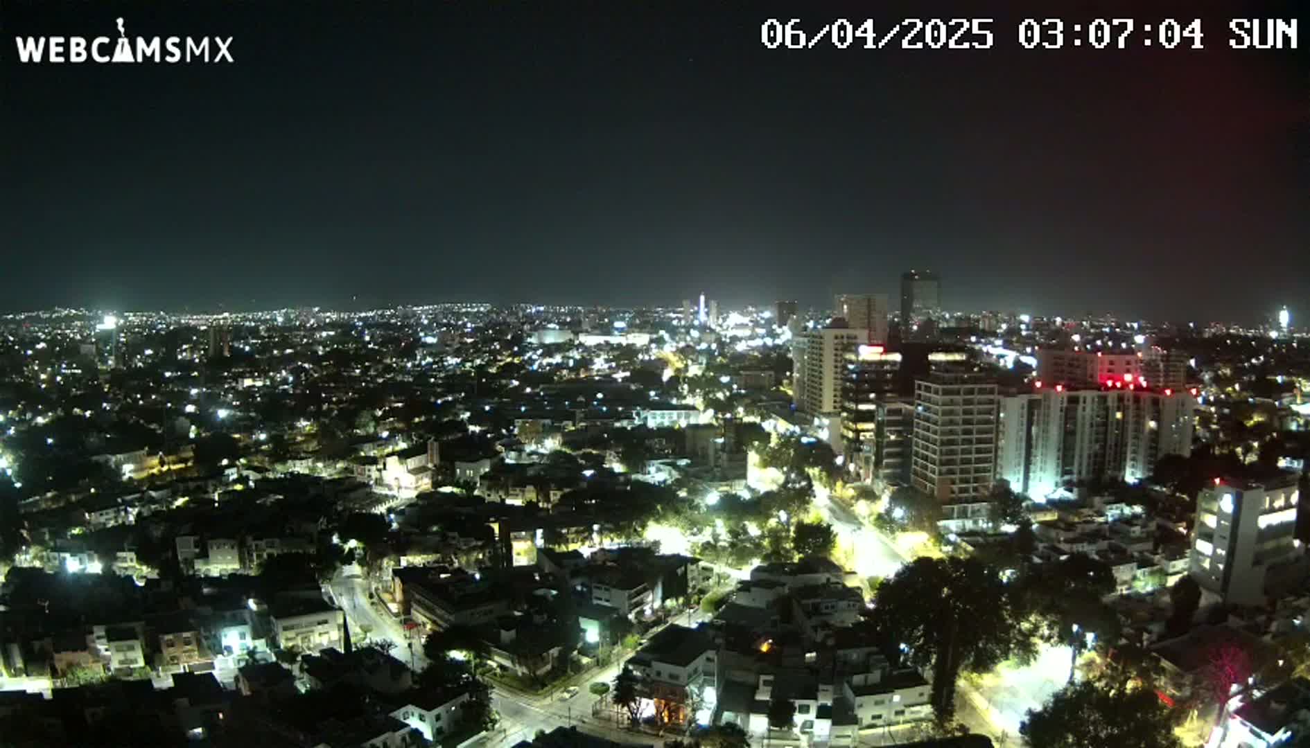 A nighttime aerial view of a city with brightly lit buildings and streets under a clear sky.