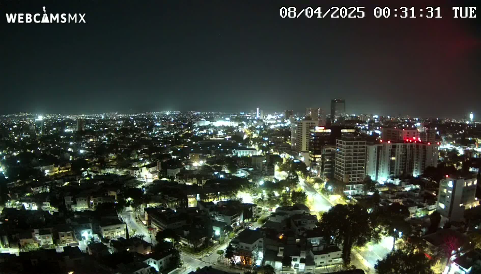 A nighttime aerial view of a sprawling city illuminated by numerous streetlights and building lights under a clear sky.