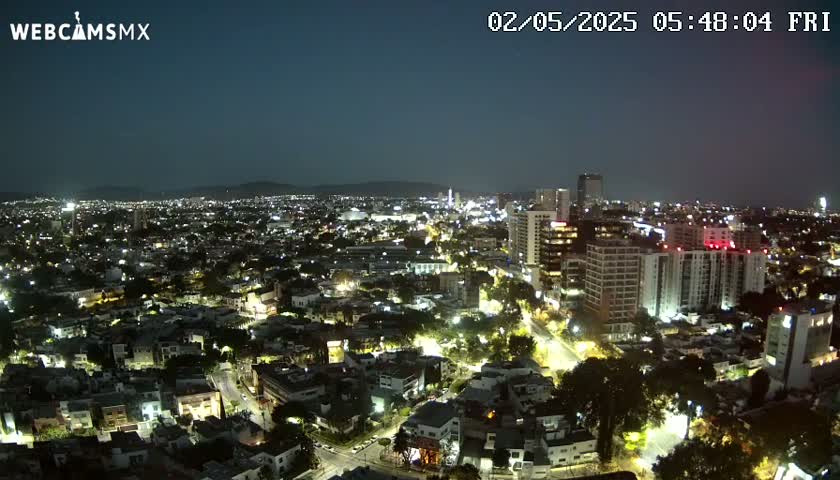 A nighttime aerial view of a city illuminated with streetlights, under a dark, clear sky.