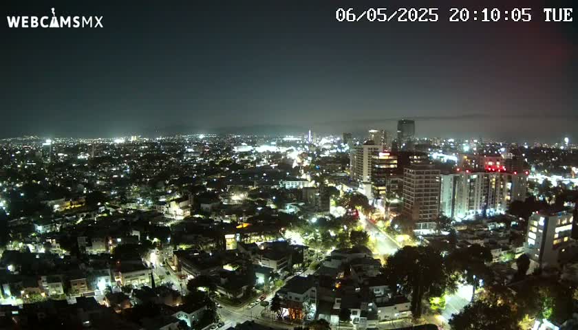 A nighttime, aerial view of a city illuminated by streetlights and building lights under a clear sky.