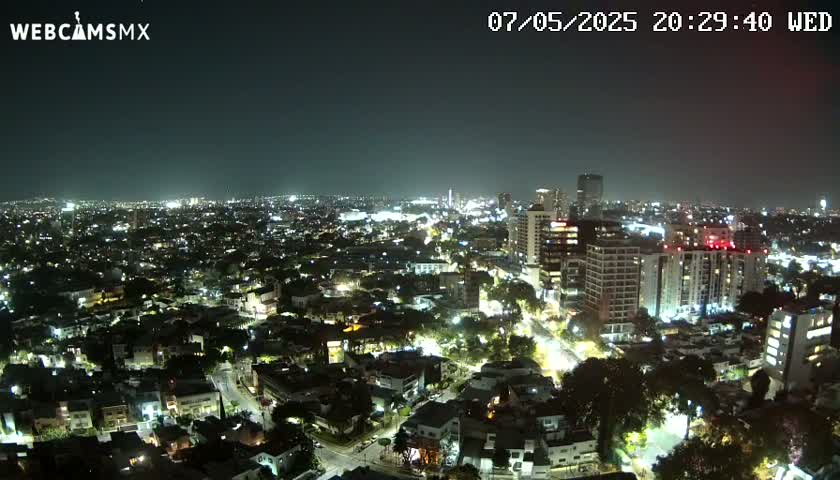 A nighttime aerial view of a city illuminated by streetlights and building lights, under a clear, dark sky.