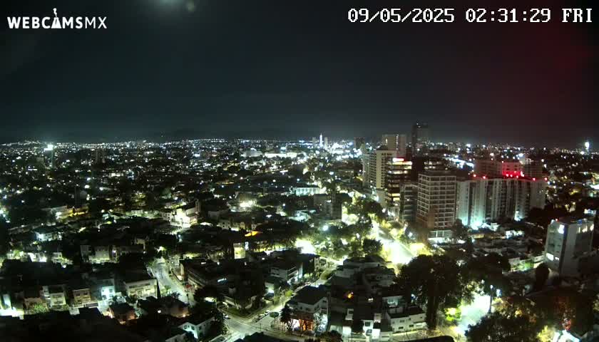 A nighttime, aerial view of a city with numerous lights illuminating buildings and streets under a clear sky.