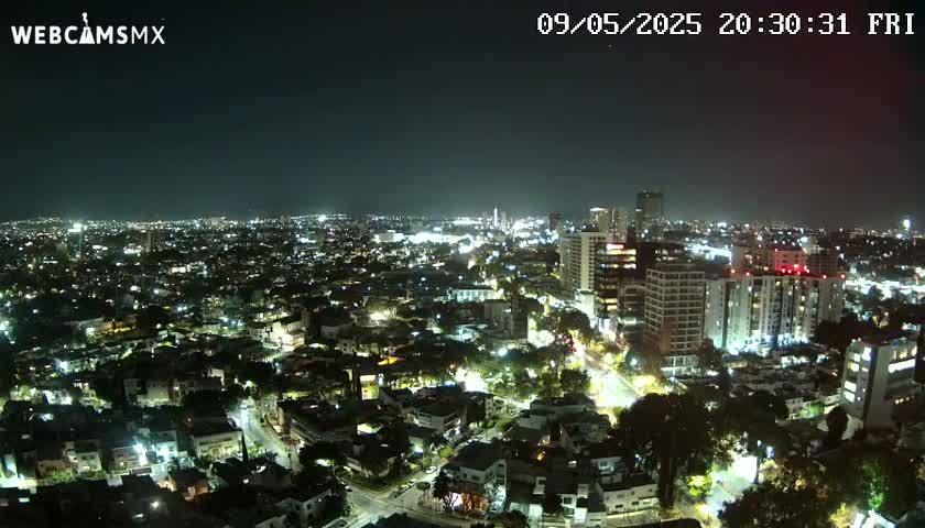 A nighttime, aerial view of a city illuminated by streetlights and building lights under a clear sky.