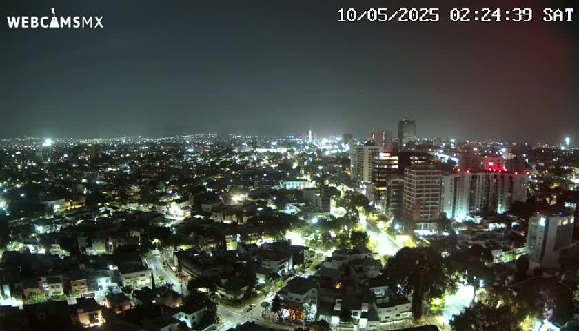 A nighttime, aerial view of a city illuminated by streetlights and building lights under a clear sky.