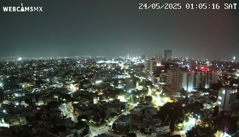 A nighttime aerial view of a city illuminated by streetlights and building lights under a clear, dark sky.