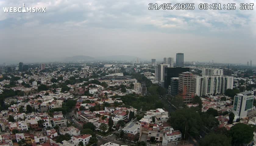 An aerial view shows a sprawling city under a hazy, overcast sky.