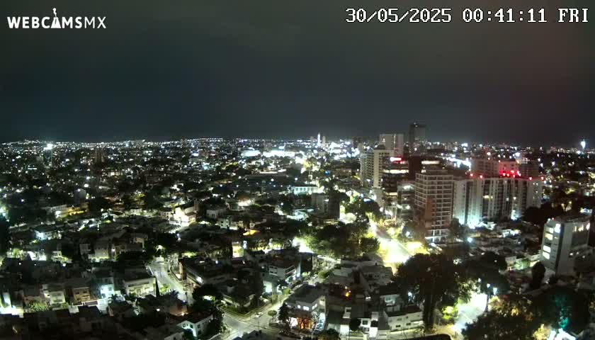 A nighttime aerial view of a city illuminated by streetlights and building lights under a clear, dark sky.