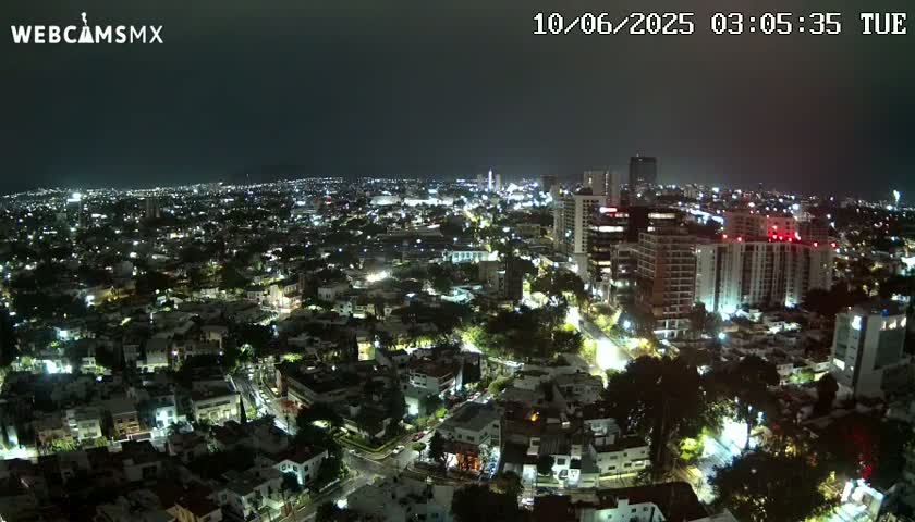 A nighttime aerial view of a city illuminated by streetlights and building lights under a dark, clear sky.