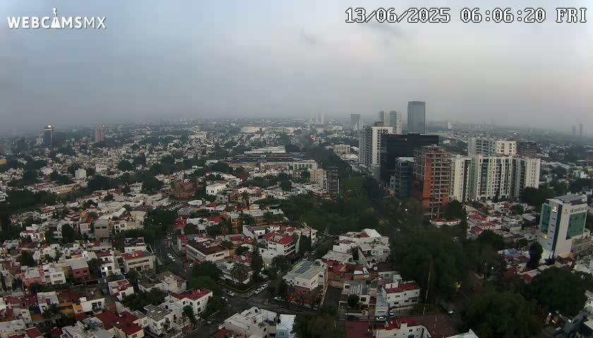 A hazy, early-morning view of a sprawling city, showing a mix of low-rise buildings and taller structures.
