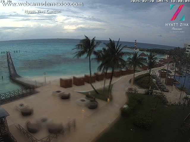An overcast day shows a resort beach with palm trees, turquoise water, and outdoor furniture.