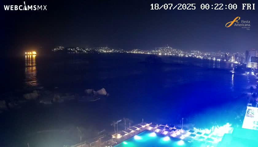 A nighttime coastal view shows a city skyline across the water, a brightly lit ship offshore, and a poolside area with illuminated cabanas and a swimming pool in the foreground.