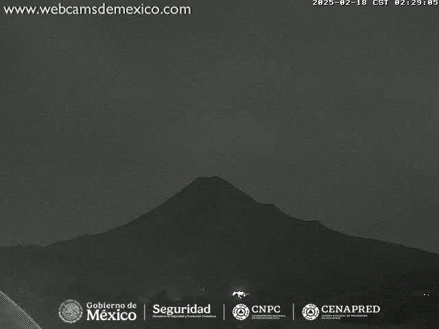 A dark, silhouetted volcano is visible under a dusky, night sky.