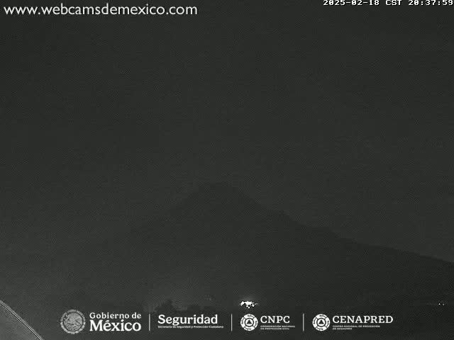 A nighttime, low-light image shows a dark, mountainous landscape under a mostly clear sky.
