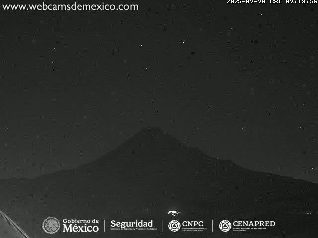 A dark, starlit night reveals a large, silhouetted mountain in the distance.