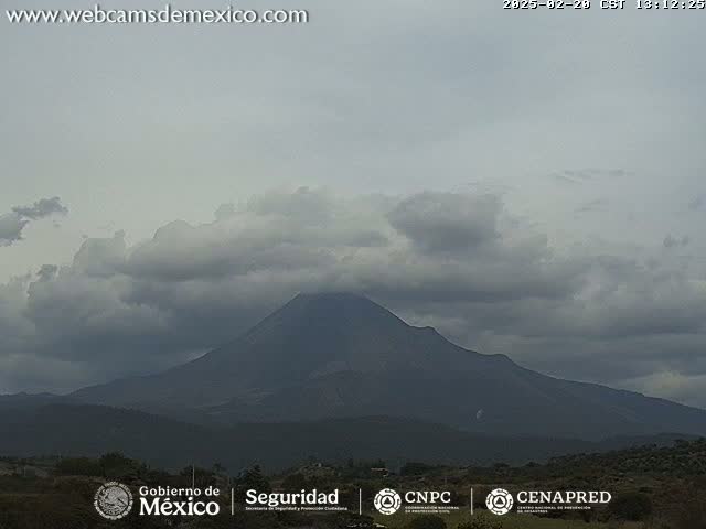 A dark, overcast sky hangs over a large, dark-colored mountain range.