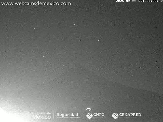 A dark, nighttime image shows a dimly lit mountain range under a clear, starlit sky.