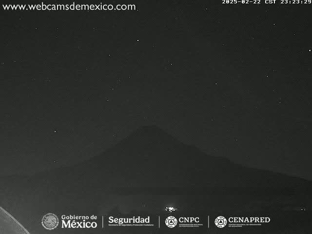 A dark, nighttime view shows a mountain silhouetted against a clear, starry sky.