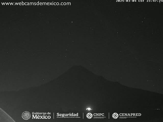 A nighttime, clear-sky view of a dark mountain range silhouetted against a starry sky.