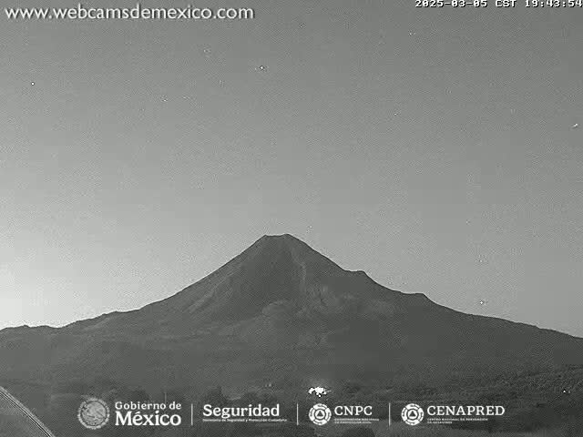A grayscale image shows a large, dark volcano under a twilight sky.