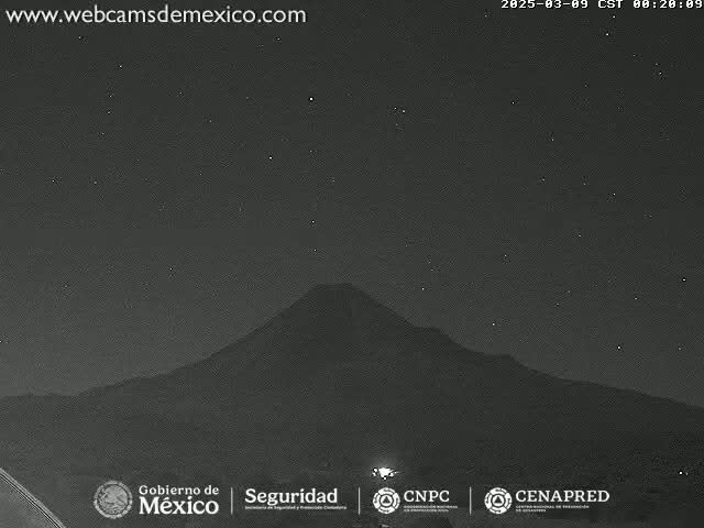 A nighttime view of a large mountain silhouetted against a clear, starry sky.