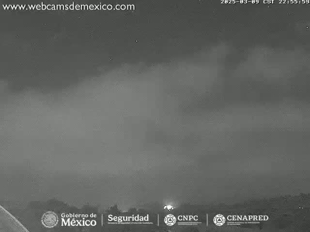 A nighttime, overcast sky with a few faint lights visible on the horizon.