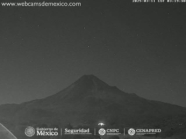 A large, dark mountain is silhouetted against a clear, starlit night sky.