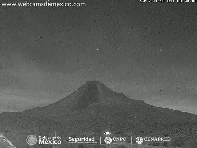 A large, dark volcano is visible under a night sky with a few stars.
